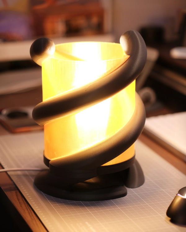 Coil Lamp — black 3D-printed spiral wrapped around a glowing translucent orange shade