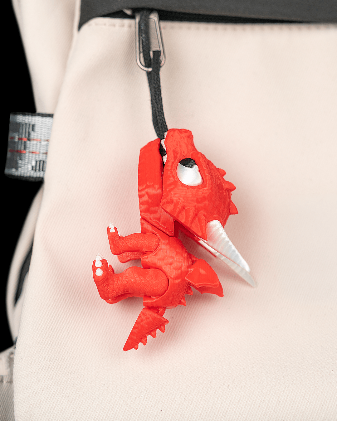Tiny Fang dragon charm clipped to a backpack, showing its size in everyday use