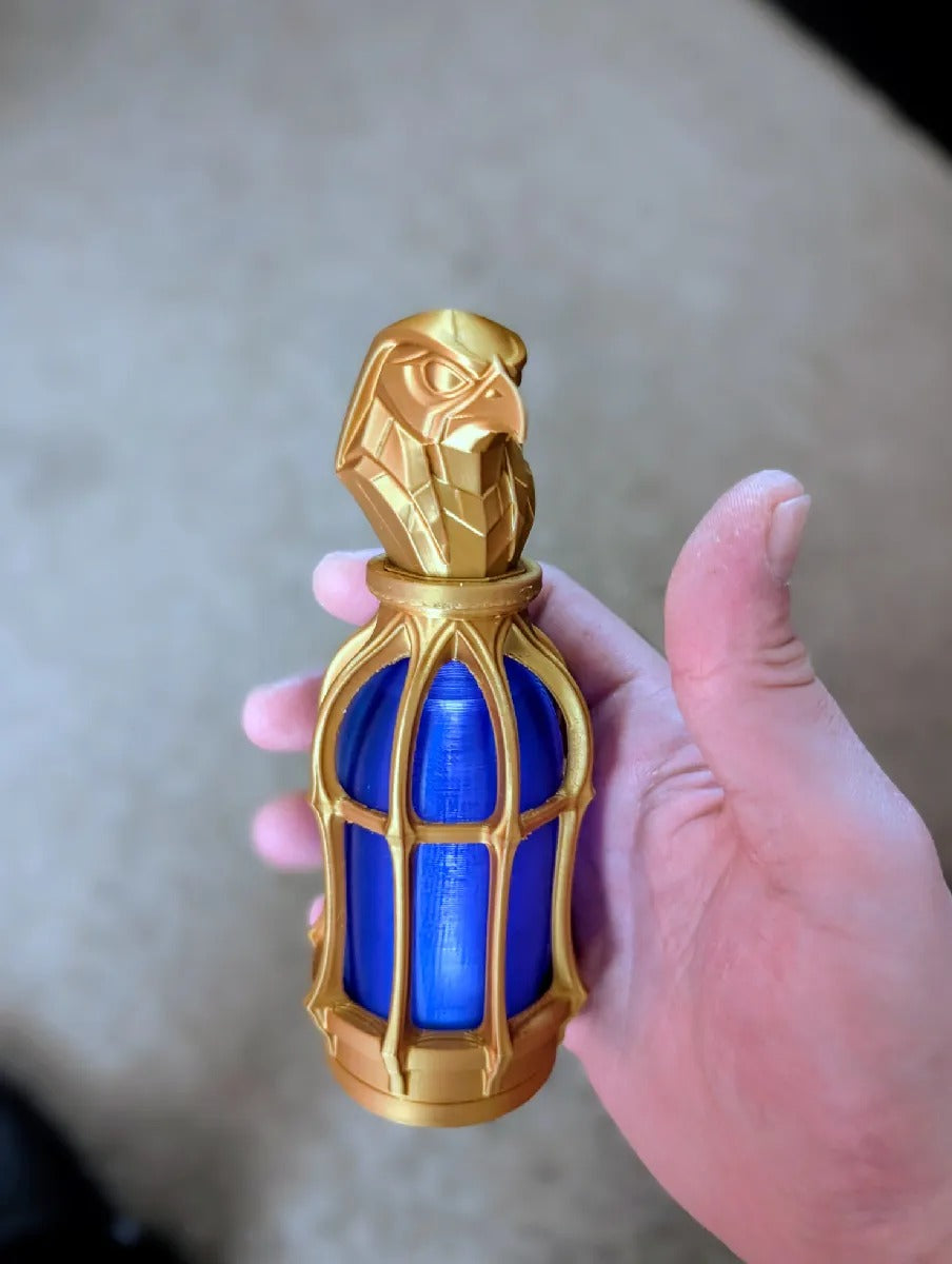 Gothic Tealight Lantern — gold lantern with Horus falcon topper and blue diffuser, held in hand for scale
