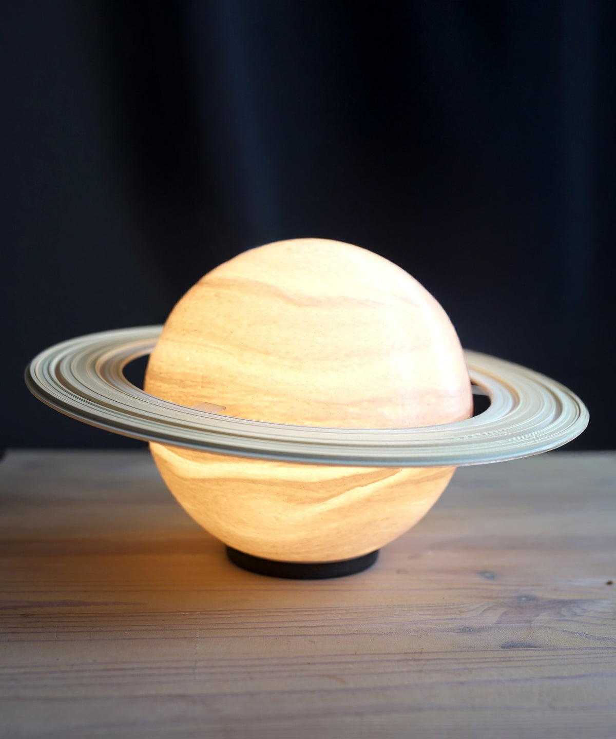 Saturn Planet Lamp — lit with a pale ring on a wooden table