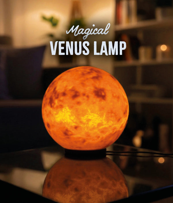 Venus Planet Lamp — glowing warm orange on a glass table